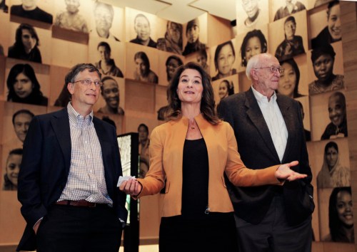 Melinda Gates lifts a pail of clean water demonstrating a display during a media tour while her husband Bill Gates stands nearby during a tour of the new visitor center at the Bill and Melinda Gates Foundation campus in Seattle